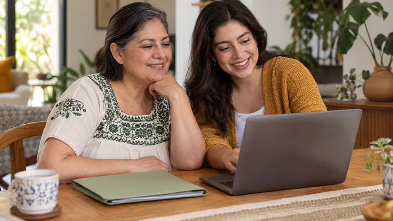 Madre e hija adulta preparando una carpeta de documentos en casa.